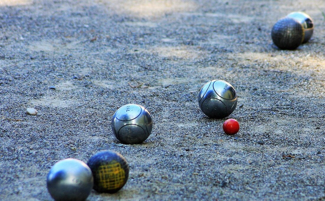 Boule-Kugeln liegen auf einem Spielfeld im Freien.